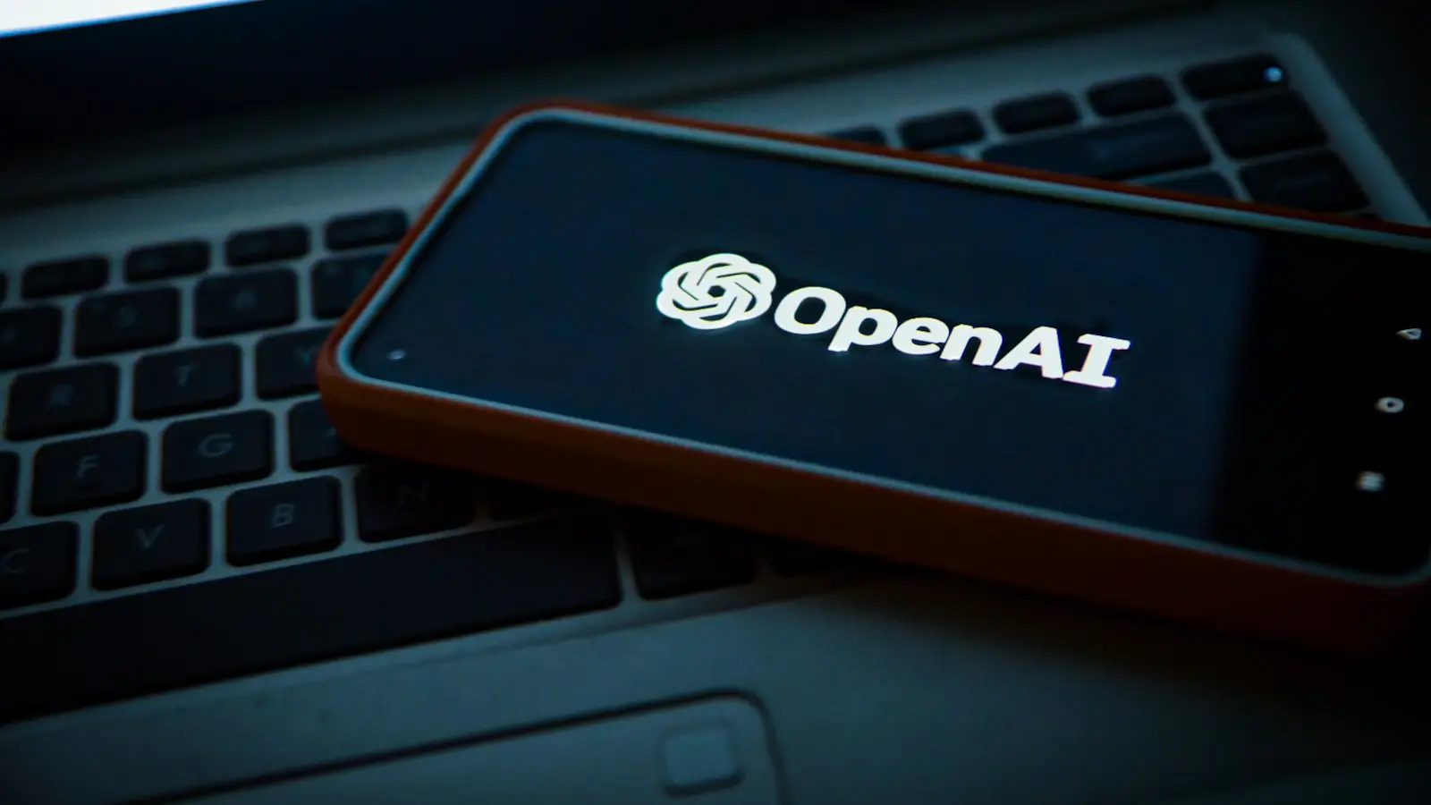 Telefon z logo OpenAI leżący na klawiaturze laptopa