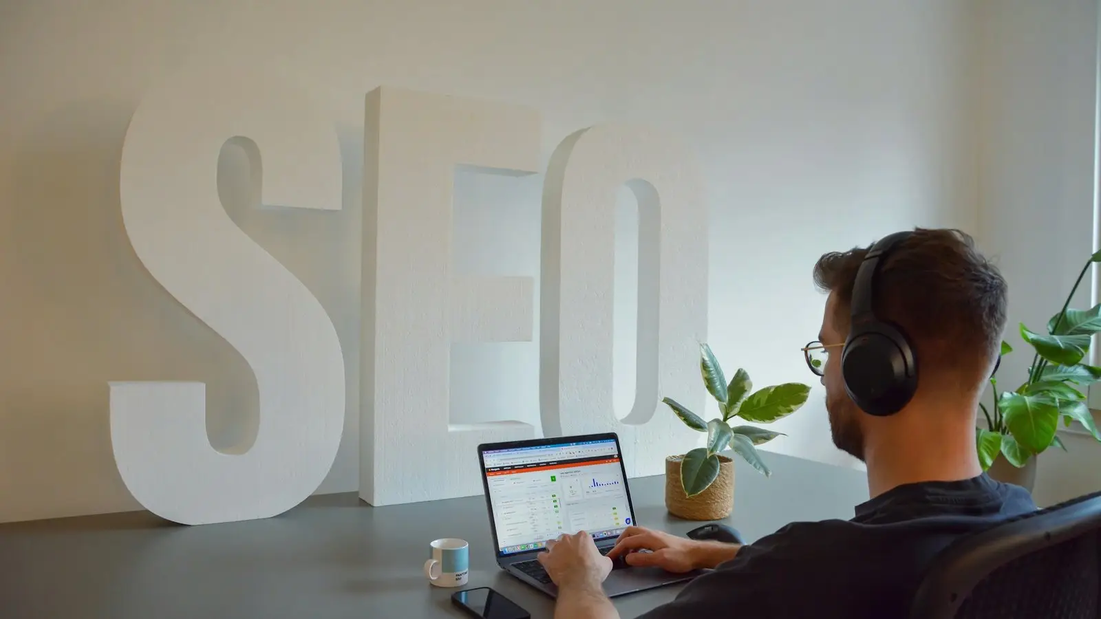 Specjalista pracuje na laptopie przy dużym napisie SEO