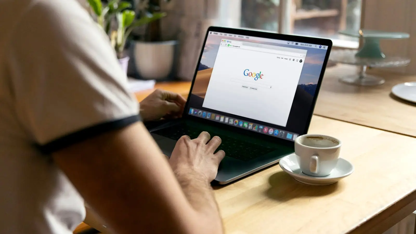 Osoba przegląda wyszukiwarkę Google na laptopie przy kawie