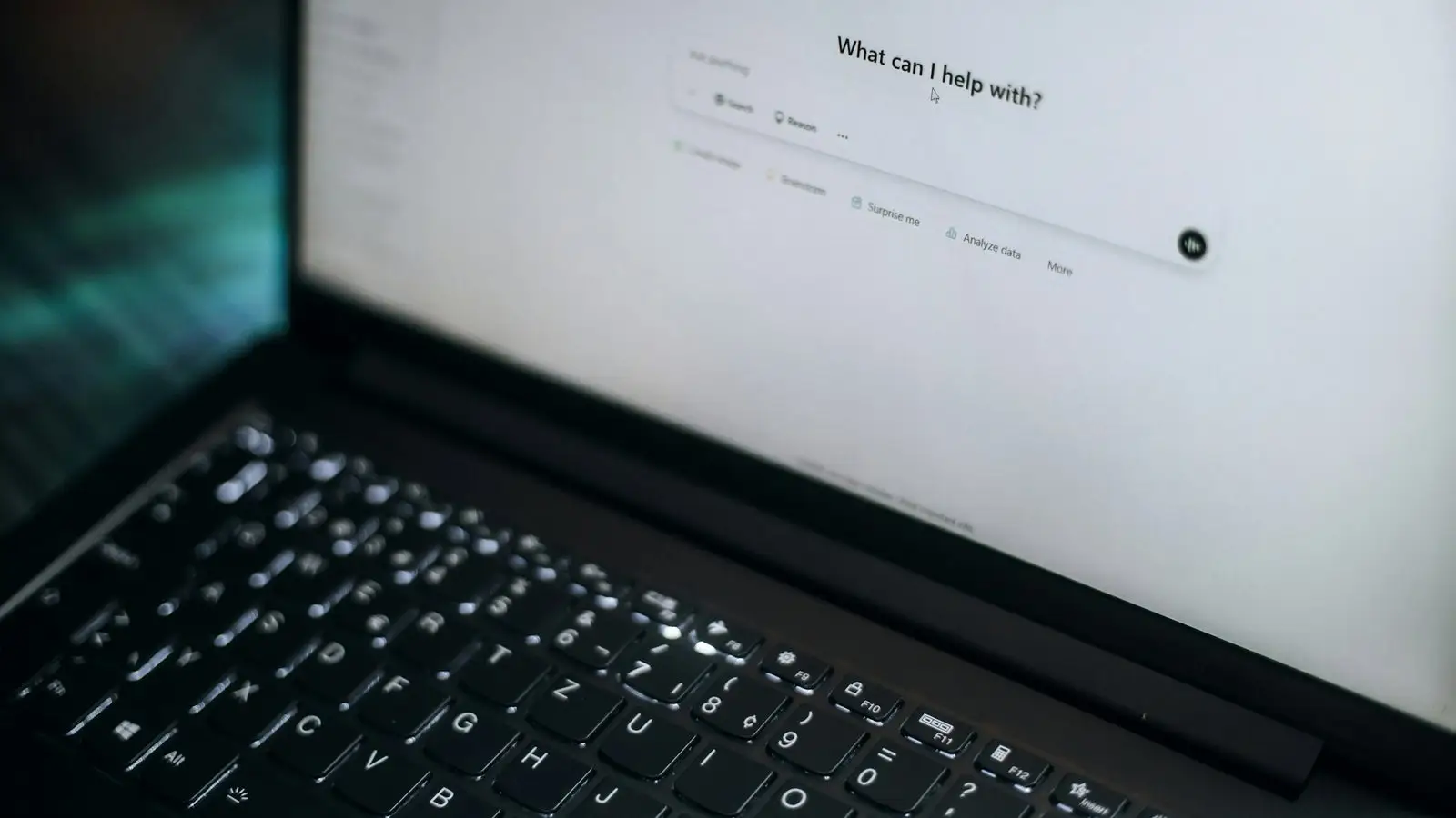 Laptop z otwartym oknem czatu AI z pytaniem, w czym może pomóc